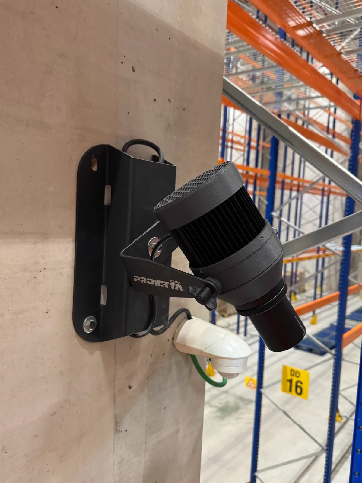 Proietta gobo projector with a motion detector, mounted on a concrete column in the warehouse